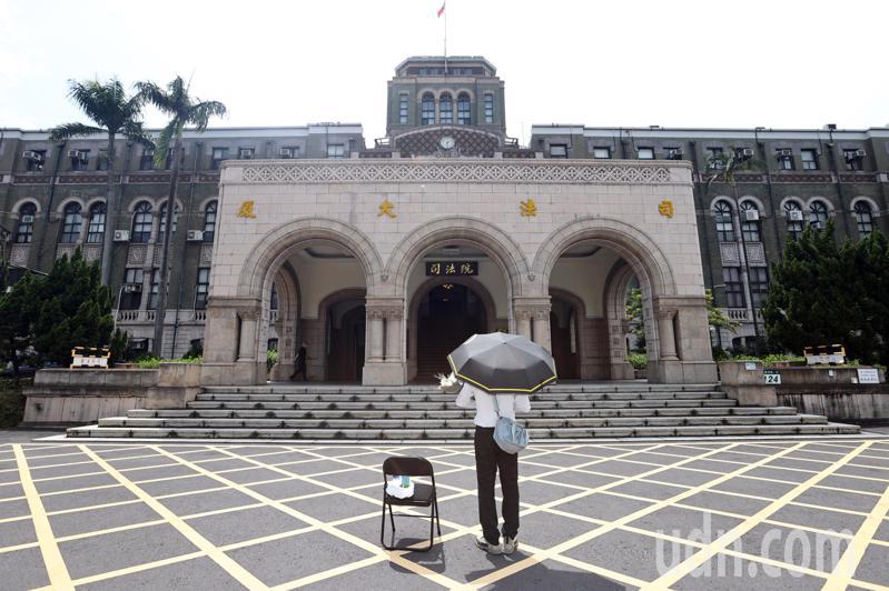 基隆地院法官李岳捧著一束白花、撑著黑伞在司法院前广场「伫立」，据了解，他将站上1天。记者杜建重／摄影