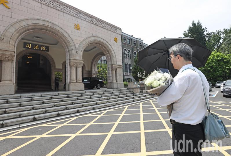 基隆地院法官李岳捧著一束白花、撑著黑伞「伫立」在司法院前广场，他向媒体表示，没有要发表声明或谈话。记者杜建重／摄影