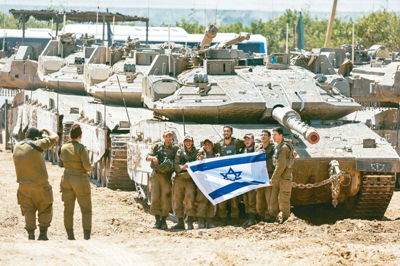 以色列官兵九日在該國南部與加薩走廊邊界地區，拿出國旗與戰車合影。以軍可能大規模入侵拉法，使美國政府首次停供彈藥給以色列。（路透）