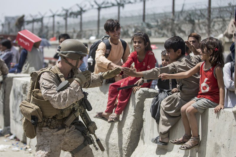 美军特种部队战士20日在喀布尔国际机场与阿富汗儿童对话。(美联社)(photo:UDN)