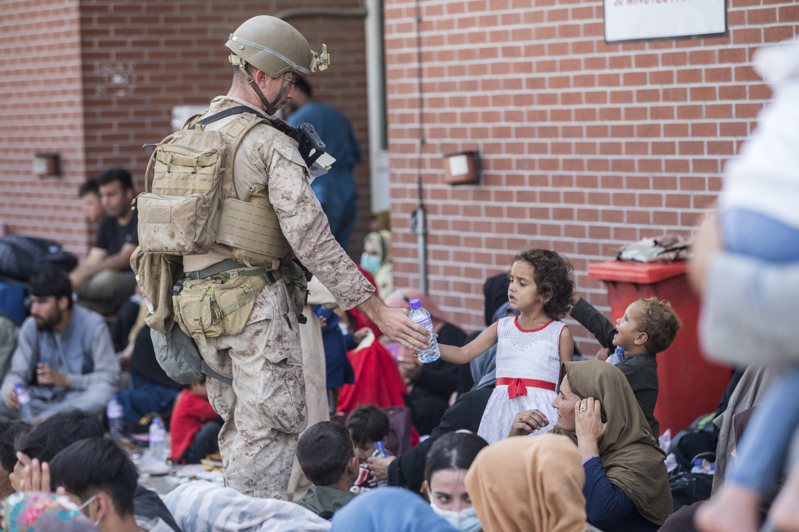美军陆战队特种部队员21日在首都喀布尔附近国际机场送水给准备登机撤离阿富汗的一群阿富汗孩童。(美联社)(photo:UDN)