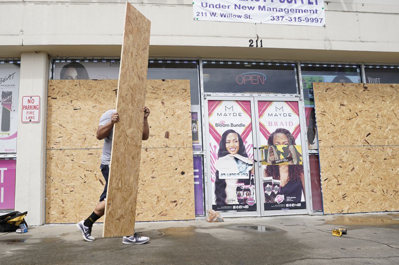 疫情升温中的路易斯安那州29日遭四级飓风艾妲(Ida)侵袭。图为一商店员工在飓风抵达前用木板封住店舖。(美联社)(photo:UDN)