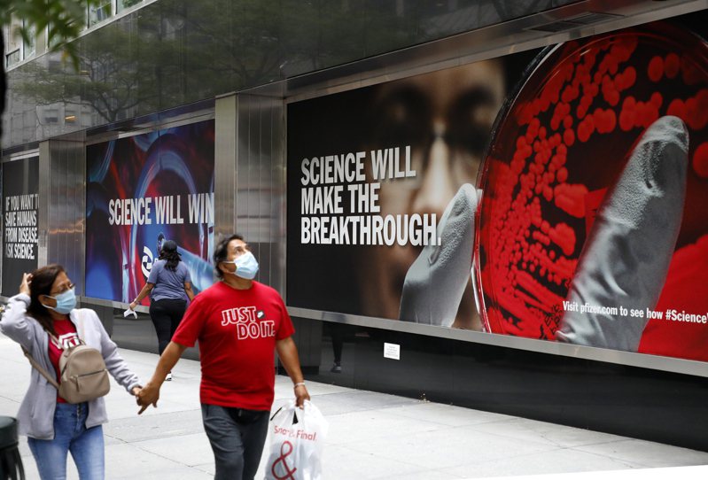 戴着口罩的民众经过位于曼哈顿的辉瑞药厂全球总部，墙上挂着新冠病毒的海报，重申「科学终将获胜」「科学终将突破」。 欧新社(photo:UDN)
