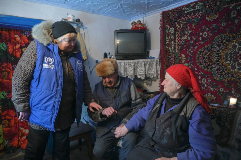 一名联合国人道救援志工（左）28日探访住在乌东前线顿涅茨克地区偏远村落的一对老夫妇。两人居住的废弃村落去年11月遭炮火攻击，正面临粮食和电力短缺。（路透）(photo:UDN)