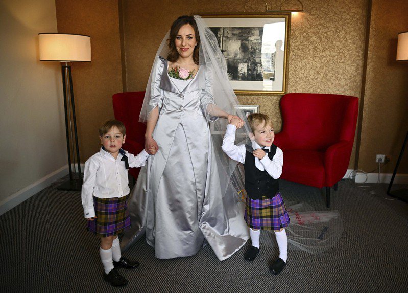 莫里斯穿上英国着名时装设计师卫斯伍德设计的婚纱，图为她与阿桑吉的两名儿子。（美联社）(photo:UDN)