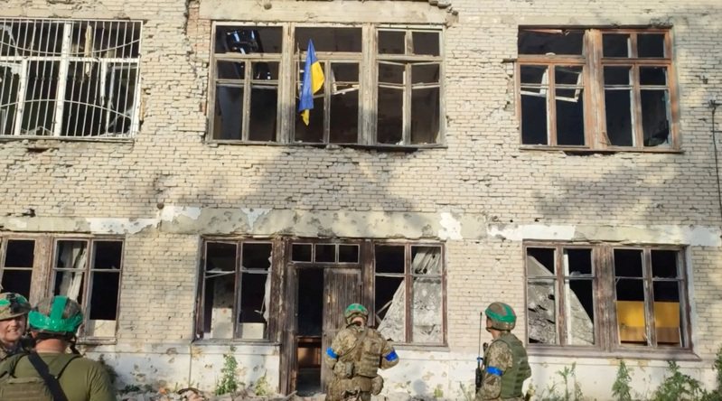 烏克蘭軍隊11日發布的一段影片中，士兵們在頓內次克州布拉霍達特內村一棟遭到轟炸過的建築升起國旗。(路透)