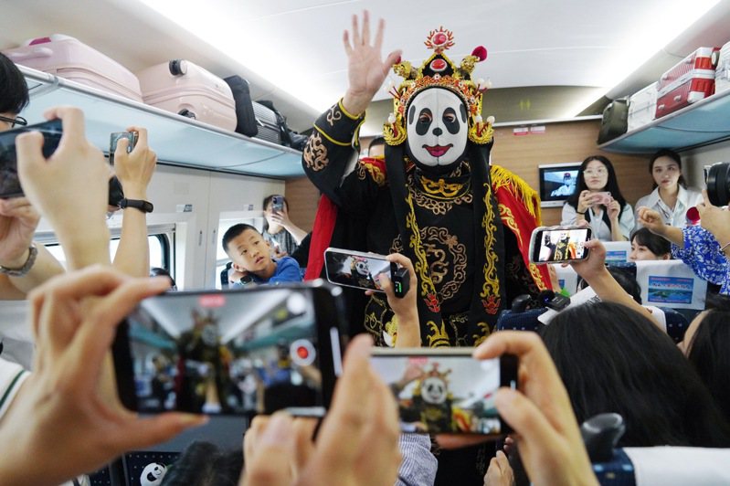 7月1日，鐵路部門首次開行成都往返香港的直達高鐵，單程運行時間約10小時。圖為乘客在成都東站開往香港西九龍站的G2963次列車上觀看川劇變臉。（新華社）
