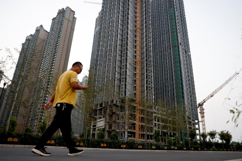 中國為救房市、穩經濟所做的「保交樓」將屆滿一年。但整體交付情形仍不如預期。圖為示意圖，一名男子走在恒大集團開發的恒大綠洲未完工的住宅樓前。（路透資料照片）