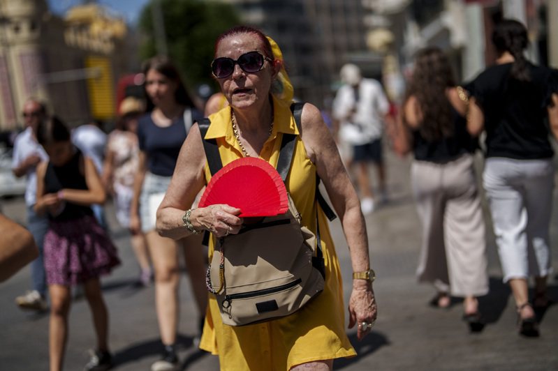 歐洲籠罩在熱浪下，民眾飽受蒸烤之苦。圖為一位女性在西班牙首都馬德里街頭揮扇驅暑。美聯社
