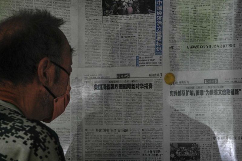 一名北京民眾正在閱讀環球時報上，批評美對中投資禁令文章。(美聯社)