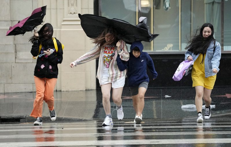 受到颶風減弱的熱帶風暴帶來龐大水氣，南加洛杉磯20日降下大雨，行人冒著風雨穿過好萊塢大道。 （美聯社)