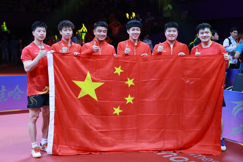 26日在杭州亞運乒乓球男子團體決賽，中國隊以3比0戰勝韓國隊獲得金牌。圖為中國隊選手馬龍、林高遠、教練員王皓、選手王楚欽、梁靖昆、樊振東（從左至右）在比賽後手舉國旗慶祝。（新華社）