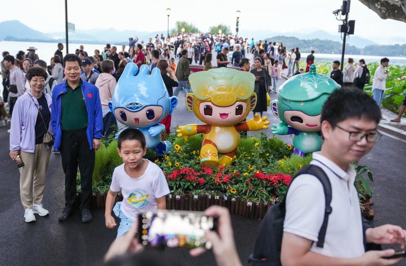 遊客在西湖邊與杭州亞運吉祥物合影。（新華社）