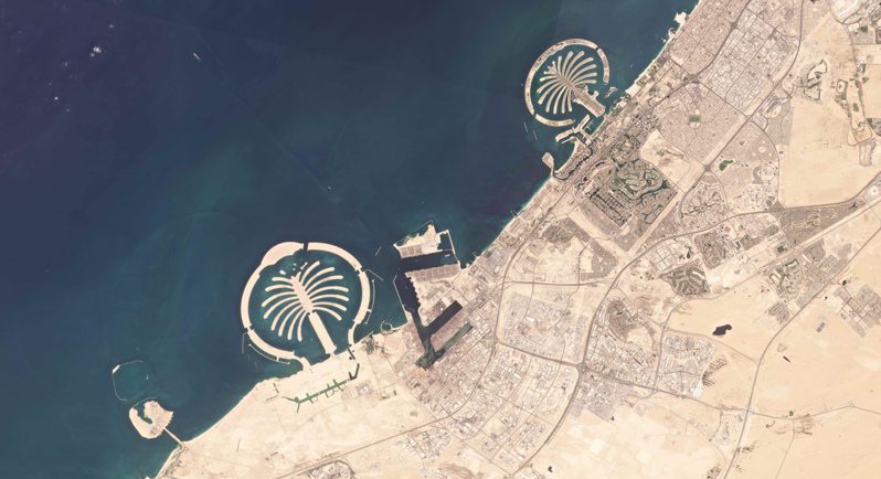 這張杜拜的衛星照片中，可看到北邊成功開發的「朱美拉棕櫚島」和南邊荒涼的「傑貝阿里棕櫚島」。（美聯社）