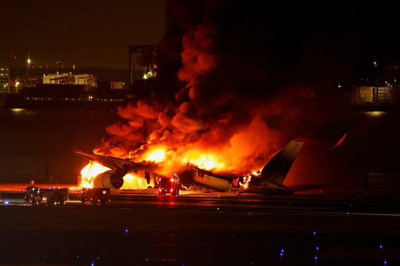 日航客機在機上乘員全數逃離後，燒成一團大火。（路透）
