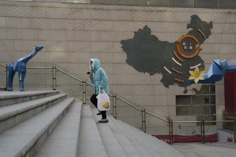 一名居民行經北京的恒大商業大樓，恒大集團29日遭香港高等法院頒令清算。(美聯社)