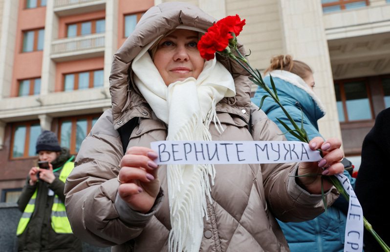 人權團體2月3日在俄國首都莫斯科舉辦示威，參加遊行的一名婦人拿著寫有「回家」的俄文標語。（路透）