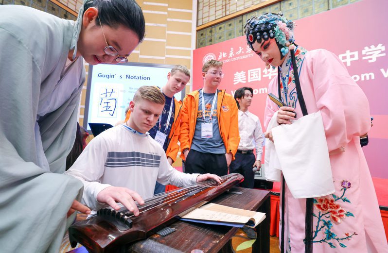 3月20日，在北京大學，中國學生在指導美國華盛頓州中學生代表團的成員彈奏古琴。（新華社）