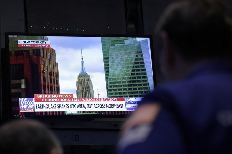 紐約證交所的電視螢幕不斷出現地震的新聞快報。（路透）