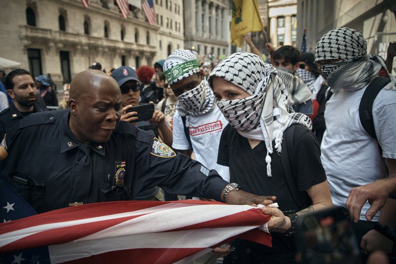以哈衝突持續不停，拜登府支持以色列政策，引發支持巴勒斯坦的選民不滿，全美各地展開示威抗議。圖為在支持巴勒斯坦人士本月15日佔據紐約市證交所示威時，維安的警員試圖制止拉扯美國國旗。美聯社