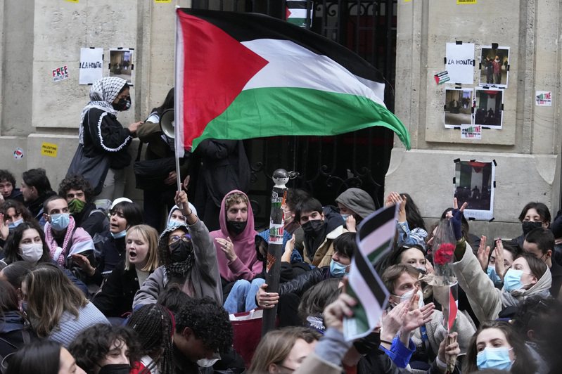巴黎政治學院26日晚間遭到示威學生占領，圖為一名學生揮舞巴勒斯坦旗幟。 （美聯社）