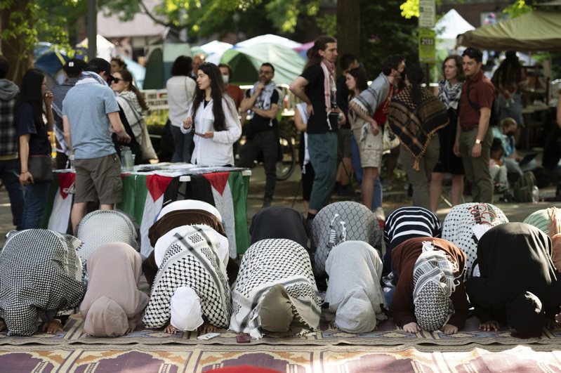 穆斯林社團人士與反猶反以挺巴的示威學生28日在喬治華盛頓大學校園裡祈禱。(美聯社)