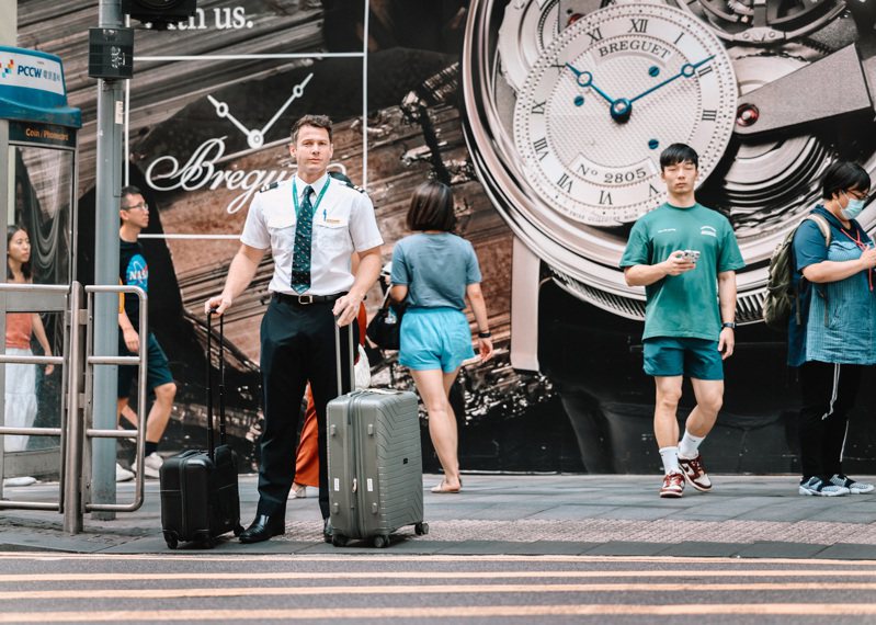 香港自2022年底推出一系列搶人才措施，至今有近12萬名人才抵港，當中有不少來自英國、澳大利亞、加拿大等地；圖為一名空乘人員在中環鬧市出行。（中通社）
