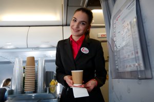一名空服員在飛機上將咖啡遞給乘客。路透