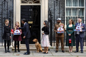 英國首相蘇納克（左三）去年10月在首相邸外向皇家退伍軍人籌款協會購買了一個小狗別針，夫人墨提（中）牽著拉不拉多犬諾瓦站在一旁。路透