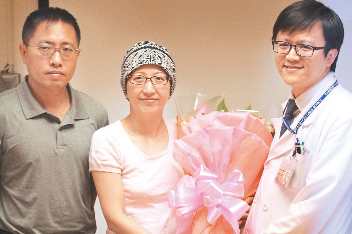 罹患乳癌的楊姓婦人（中）贈花給台大雲林分院腫瘤醫學部陳國興（右），醫院也準備蛋糕歡慶她重獲新生。