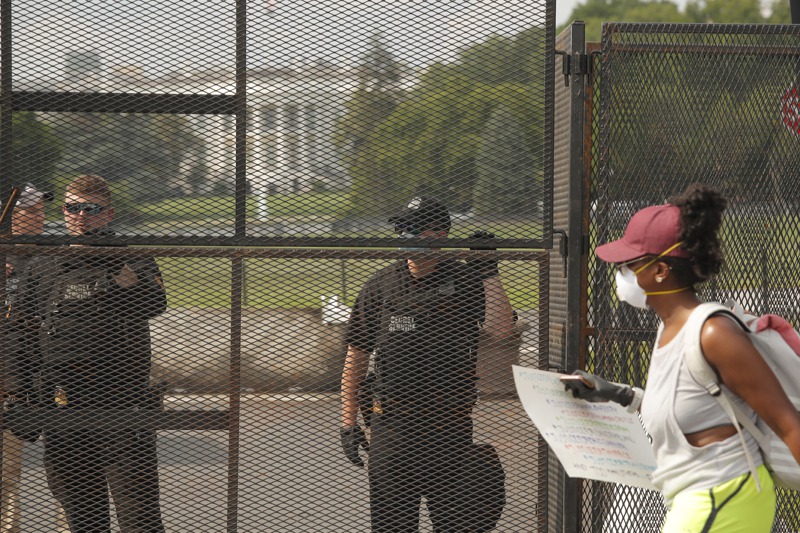 一名示威者6日經過設在白宫外圍，有約2.4公尺高的金屬圍籬。美聯社