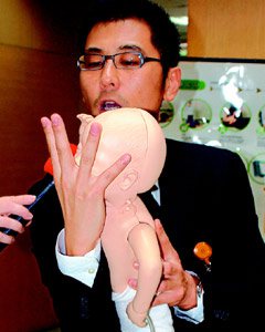 醫師賈蔚示範嬰兒哈姆立克急救法。步驟1：用手扶住臉部，準備倒置。（記者賈寶楠／攝影）