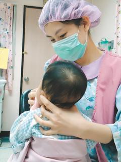 陳麗如作品「寶貝乖乖」中，護理人員正在幫剛喝完奶的小嬰兒擦嘴巴。 圖／聯合醫院護理部提供