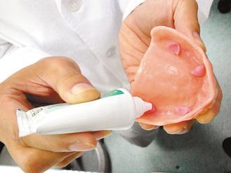 牙醫師鄭智文示範正確使用假牙黏著劑的方法，強調不當使用會傷害口腔與假牙。 記者周宗禎／攝影