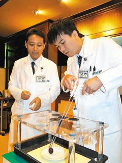 花蓮慈濟醫院婦科主任丁大清（左）解說，醫師龐&#28162;醛（右）示範單孔腹腔鏡儀器剝葡萄皮的難度。 記者范振和／攝影