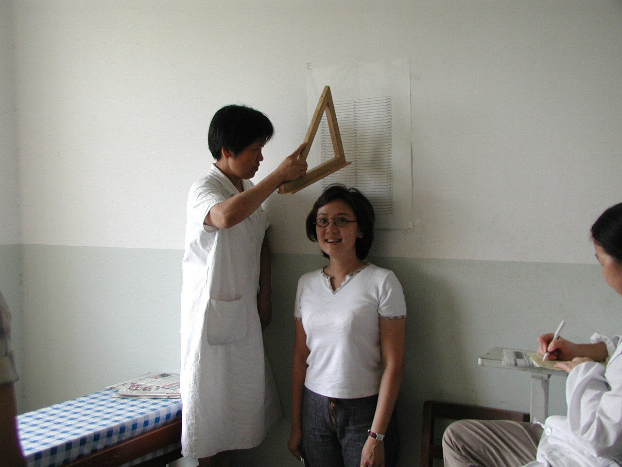 2002年9月上海復旦大學新生體檢，醫護人員用三角板充當量身高器具。