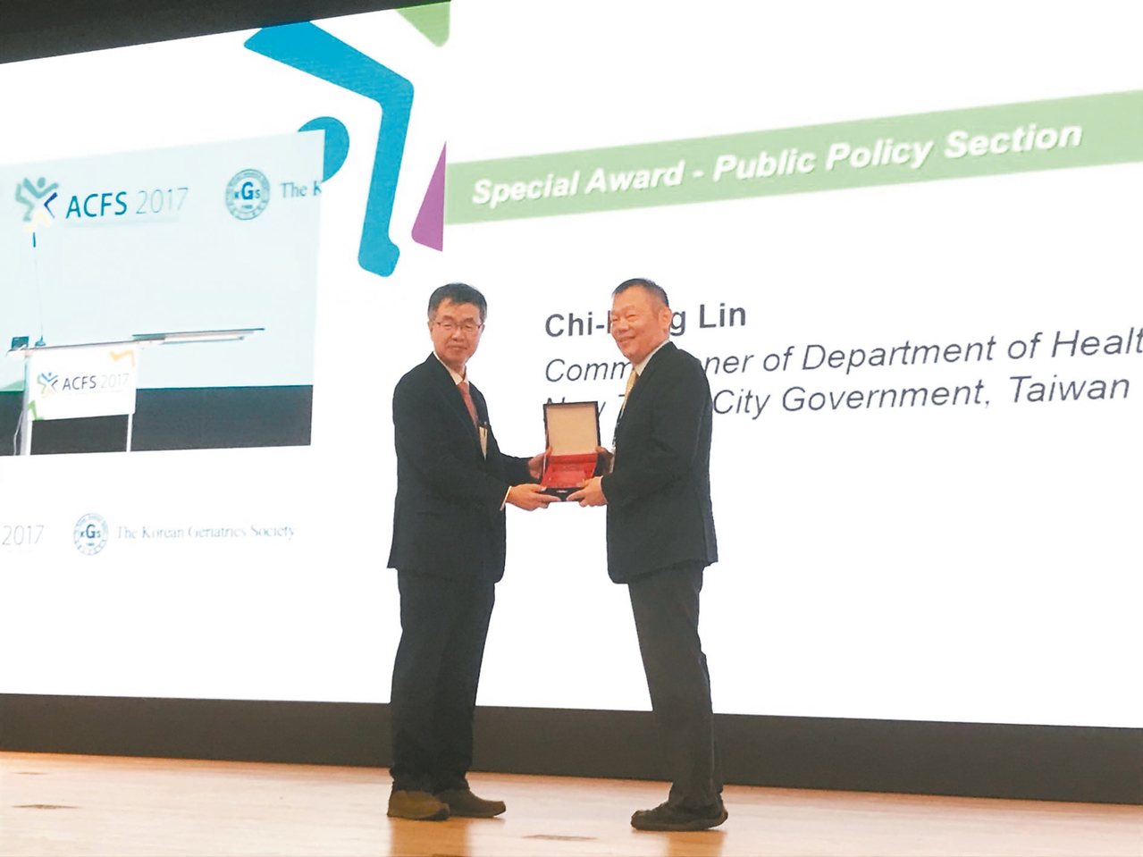新北動健康防衰獲得國際肯定，新北市衛生局長林奇宏(右)28日在南韓首爾領取「2017亞洲衰弱症及肌少症會議公共貢獻獎」。