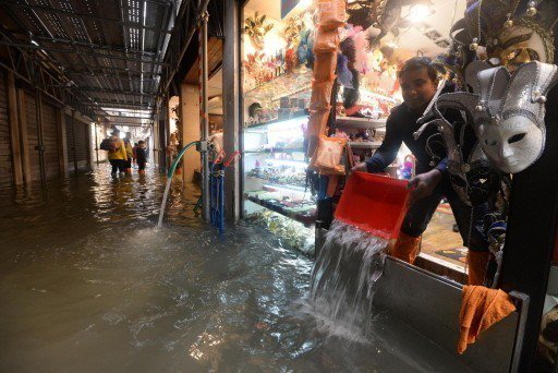 威尼斯的商家忙著把店內積水舀出屋外。 （歐新社）