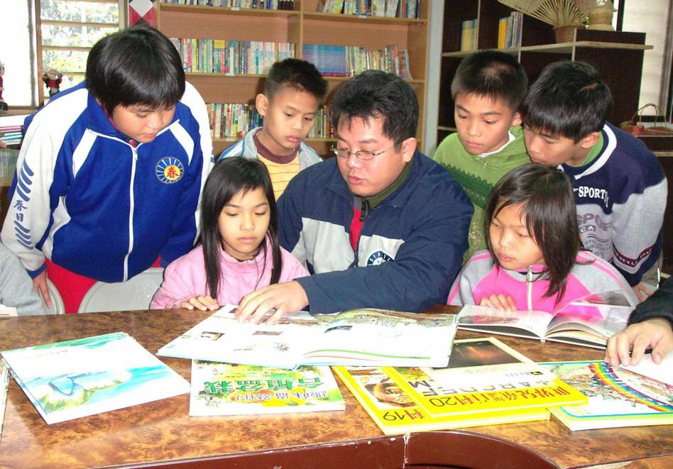 謝明賢（中）把閒置的春日部落聚會所變成兒童經常出入的圖書館，圖攝於2006年。圖／報系資料照