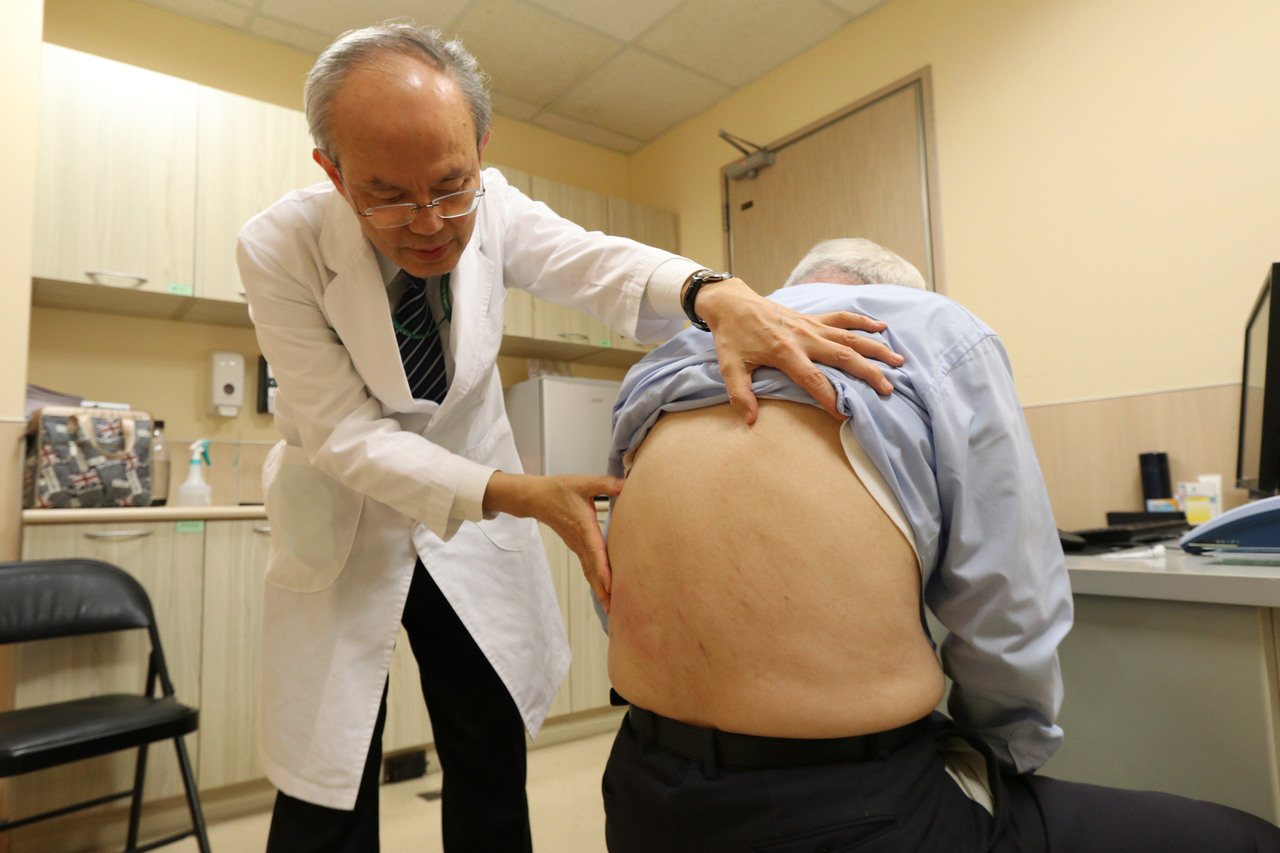 亞大醫院過敏免疫風溼科主任蔡肇基替患者檢查患部。（圖非當事人）圖／亞大醫院提供