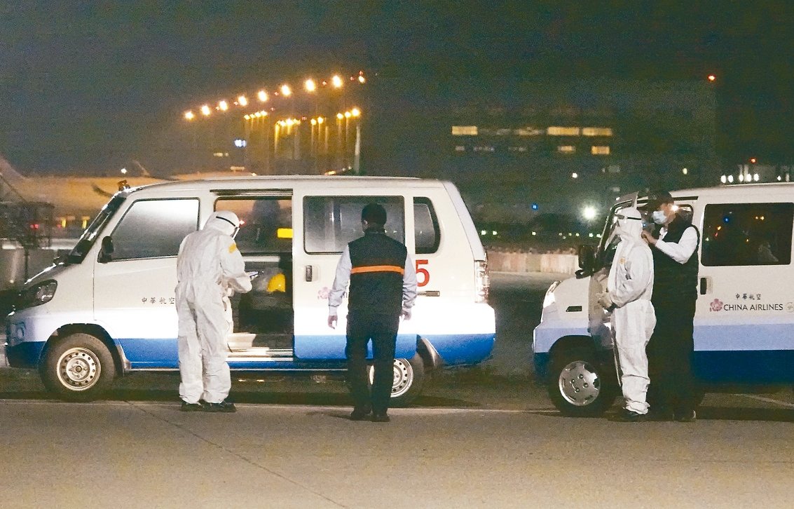 第二批武漢專機昨天深夜11時38分抵達桃園機場，準備接機的地勤人員互相幫忙穿著防護衣。
