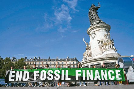 「新全球金融公約峰會」23日落幕，圖為環保團體在巴黎共和國廣場上舉布條抗議，要求停止對化石燃料相關活動提供融資。（美聯社）