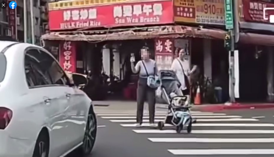 一名女子推嬰兒車過馬路時，掏出手機對著一輛白色賓士狀似錄影，警告意味濃厚，女子的舉動引發網友熱議。圖擷自《爆廢公社二館》