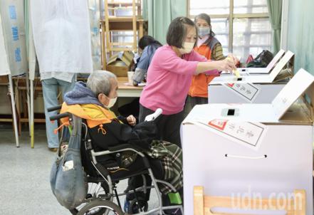 第16任總統副總統及第11屆立法委員選舉投票日，台北市大安國中投開票所投票民眾投票踴躍，行動不方便的長者坐著輪椅在家人陪同下完成投票。記者林俊良／攝影
