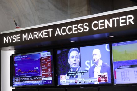 紐約證交所交易大廳螢幕看板顯示特斯拉執行長馬斯克（左）與亞馬遜創辦人貝佐斯（右）。 路透