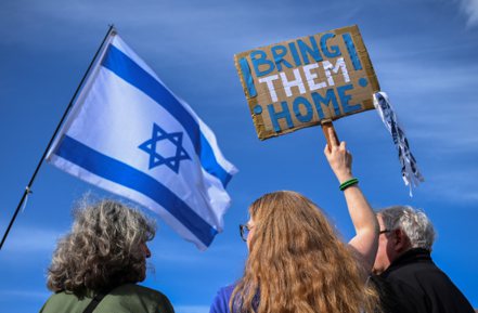 伊朗向以色列發射無人機和飛彈後，德國柏林14日街頭，人們舉著以色列國旗和標語牌，呼籲讓以色列人質回家。（路透）