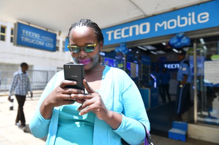傳音手機在非洲市佔率超過4成，有「非洲手機之王」之稱。圖為一名女子在肯亞首都一家傳音手機專賣店前使用手機。新華社
