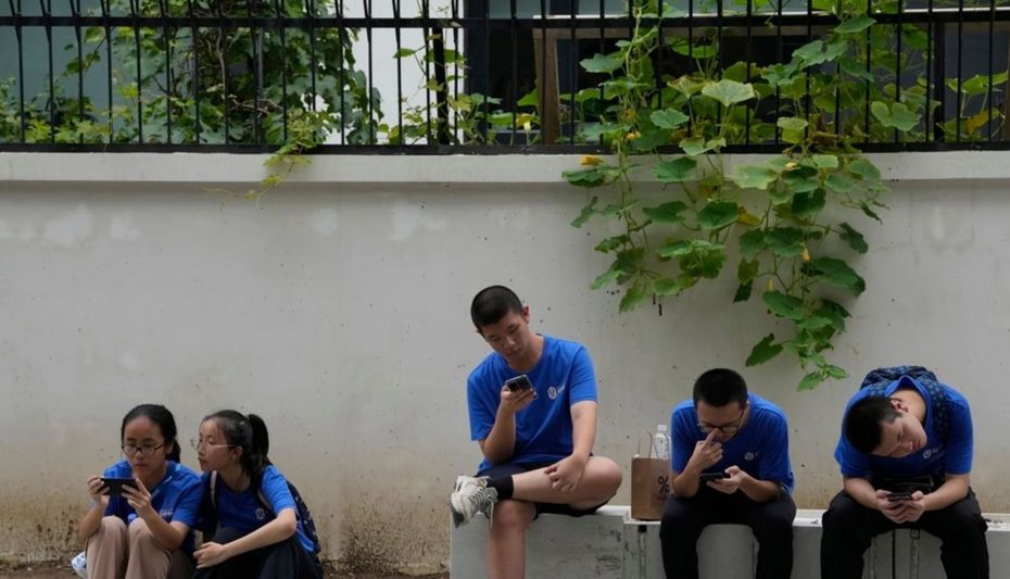 中國再出重手監管網路遊戲，圖為北京街頭年輕人在玩手機。(美聯社資料照片)