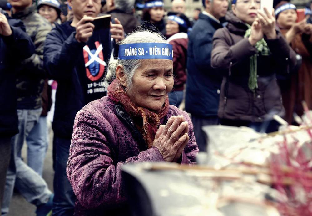 向中越戰爭陣亡越軍致意的越南老婦，她頭上綁著的標語則寫著「黃沙，邊界」。 （圖／...