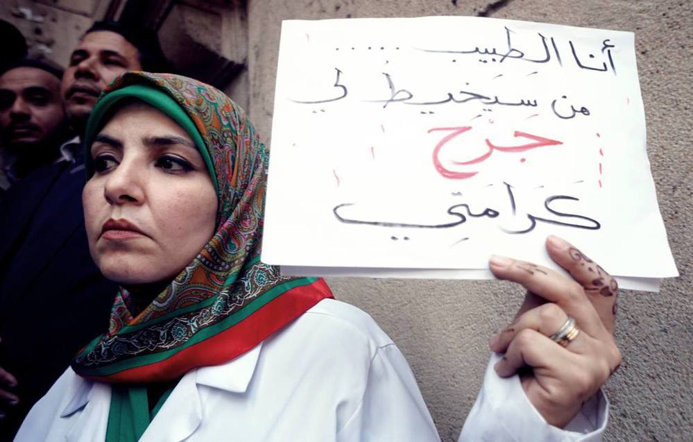 抗議的醫師，舉著標語「我是醫生...但誰又能治癒我尊嚴的傷口？」 （圖／美聯...